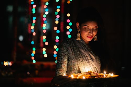 Free South Asian woman in traditional attire participating in a vibrant festival celebration with candles and lights. Stock Photo