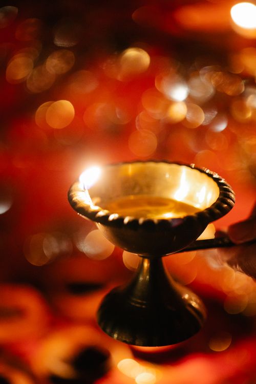 Free A glowing golden lamp held during a lively festival with sparkling bokeh in the background. Stock Photo