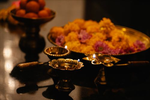 Free Close-up of traditional brass candle holders with flowers and sweets, creating a warm and festive atmosphere. Stock Photo