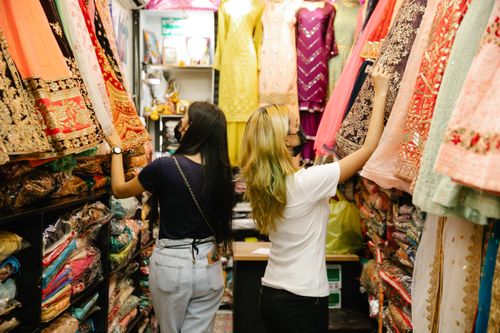 Free Two women browsing colorful traditional dresses in a boutique store. Stock Photo