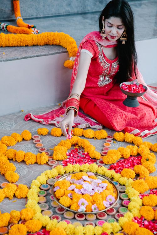 Free A woman in traditional attire decorates a vibrant rangoli with flowers and candles for a festival. Stock Photo