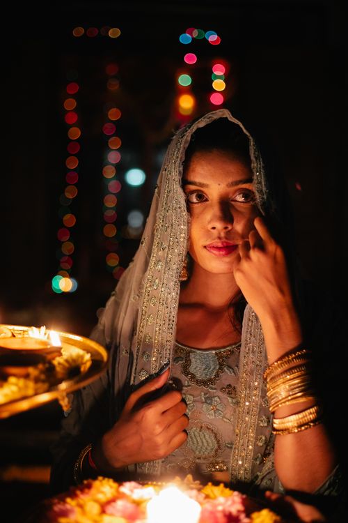 Free A woman dressed in traditional Indian clothing, illuminated by candlelight during a festive night celebration. Stock Photo