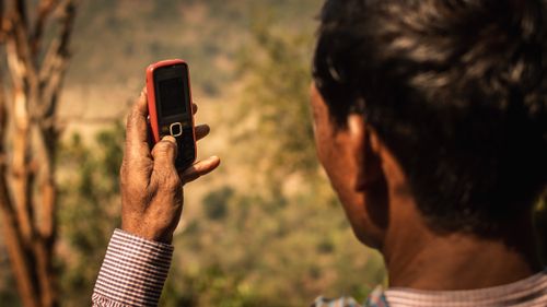 Free A man using a cellphone outdoors in rural Odisha, India. Stock Photo