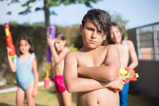 Group of kids playing with water guns in a sunny outdoor setting, enjoying summer fun.