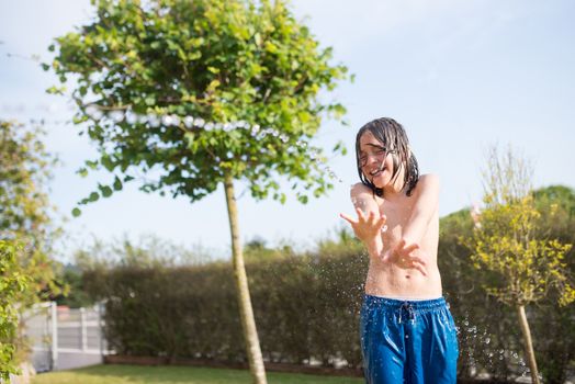A young boy having fun splashing water in a sunny outdoor setting.