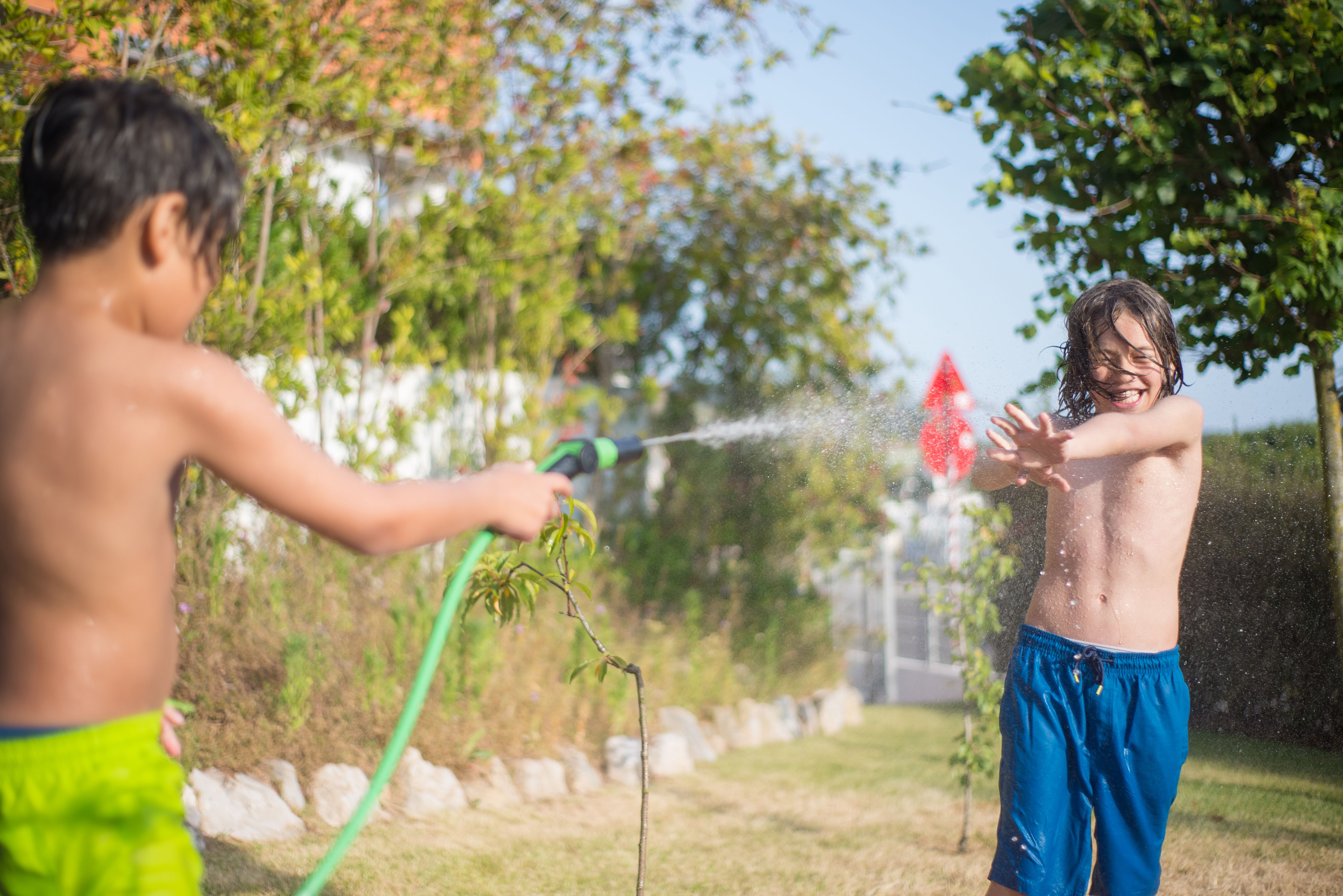 Children laughing and playing in sprinklers to beat the heat on a sunny day