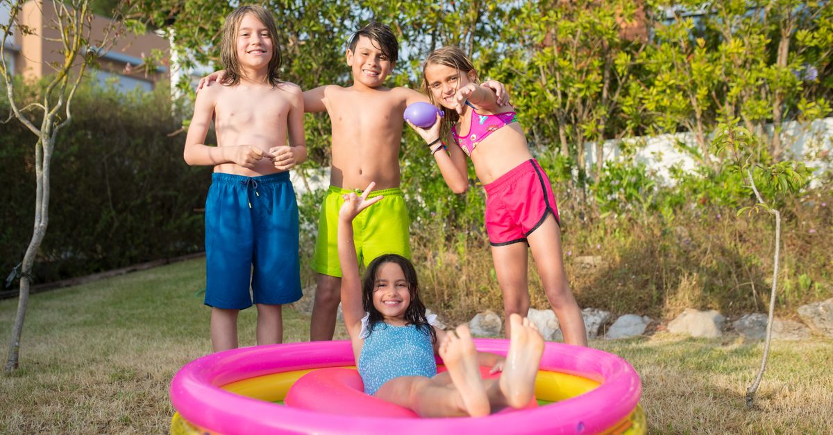 Piscina de montar no quintal Quatro crianças brincando em uma piscina inflável no quintal