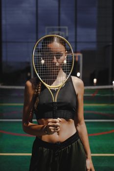 Athletic woman holding a tennis racket, standing on an indoor court in Sochi.