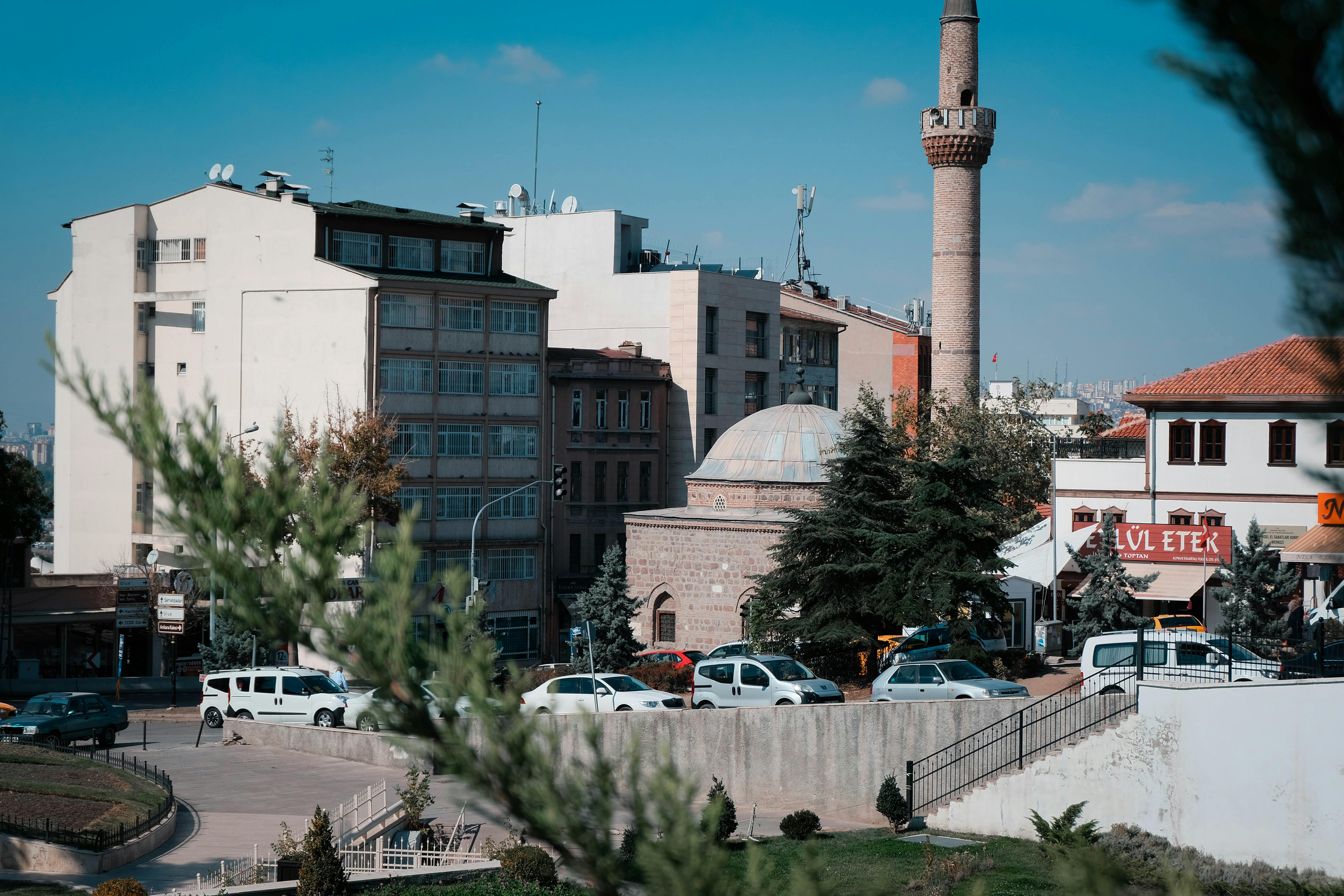 A vibrant urban scene in Ankara featuring a mosque and the surrounding cityscape on a sunny day.