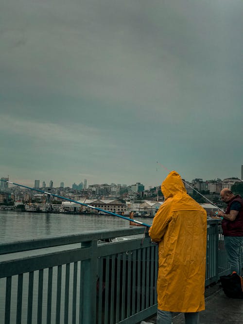 Men Fishing with Rods on City Bridge