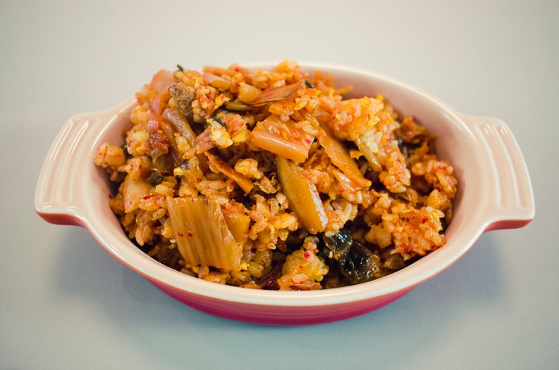 Kimchi fried rice tossed with vegetables and fried egg in a ceramic bowl