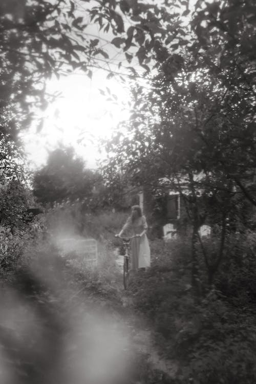 Woman Holding a Bicycle Near Trees 