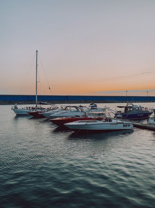 Free Speedboats docked at sunset with calm waters and blue skies. Stock Photo