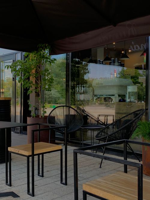Free Chic outdoor cafe area with modern glass walls and stylish furniture. Stock Photo