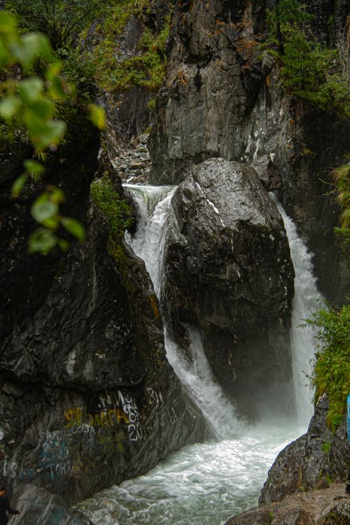 Free Beautiful waterfall cascading through rugged rocks surrounded by lush greenery. Stock Photo