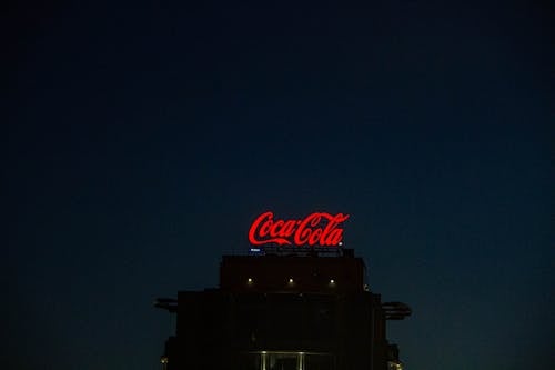 Free A Red Coca Cola Neon Light Signage on a Silhouetted Building Stock Photo