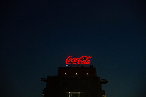 Free Illuminated Coca-Cola sign atop a building in Moscow at night. Stock Photo