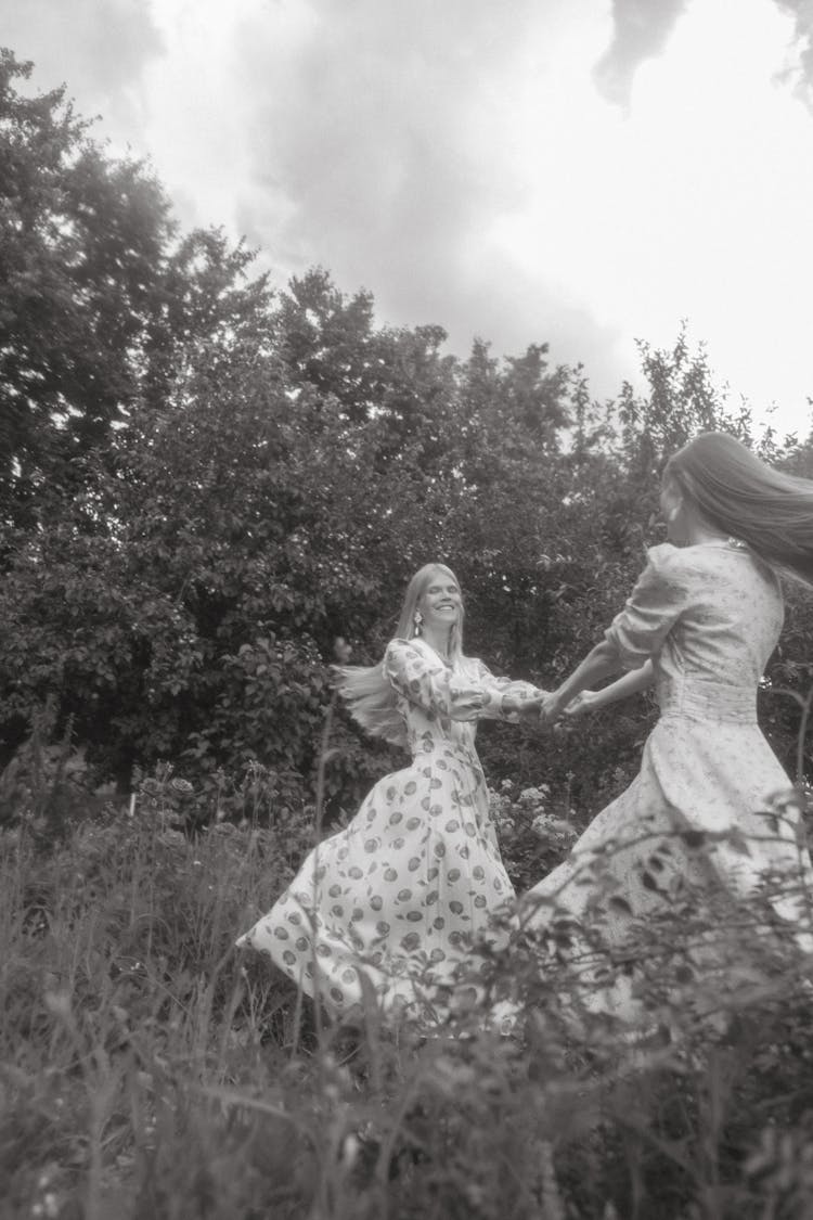 Women In Floral Dress Holding Hands While Dancing Around