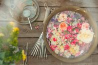 A Bowl of Water with Flowers Beside a Stainless Rake