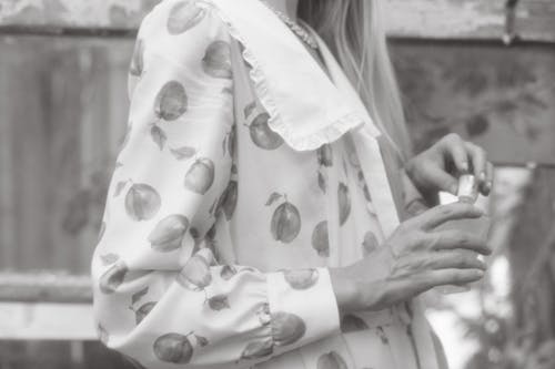 Free Grayscale Photography of a Person in Floral Long Sleeve Dress Holding a Bottle Stock Photo