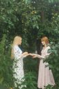 Woman in White and Green Floral Dress Standing Beside Woman in White and Green Floral Dress