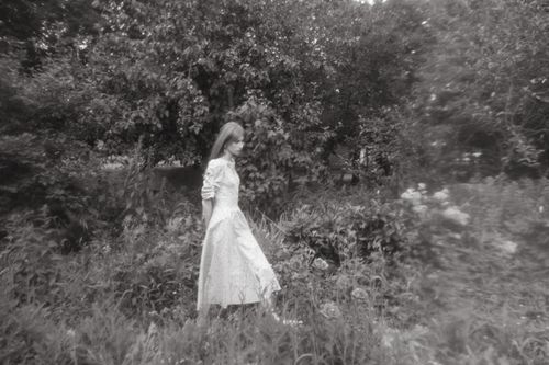 Free Woman in a white dress walking through a lush field, captured in black and white. Stock Photo