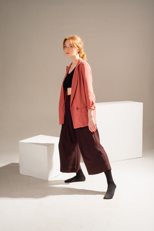 Free Fashionable woman in stylish attire stands near minimalist blocks, embodying modern elegance. Stock Photo