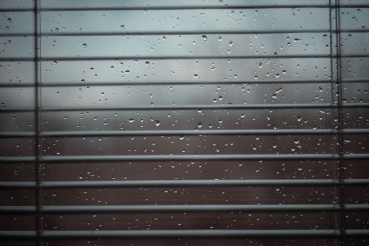 Window Blinds Behind Wet Glass