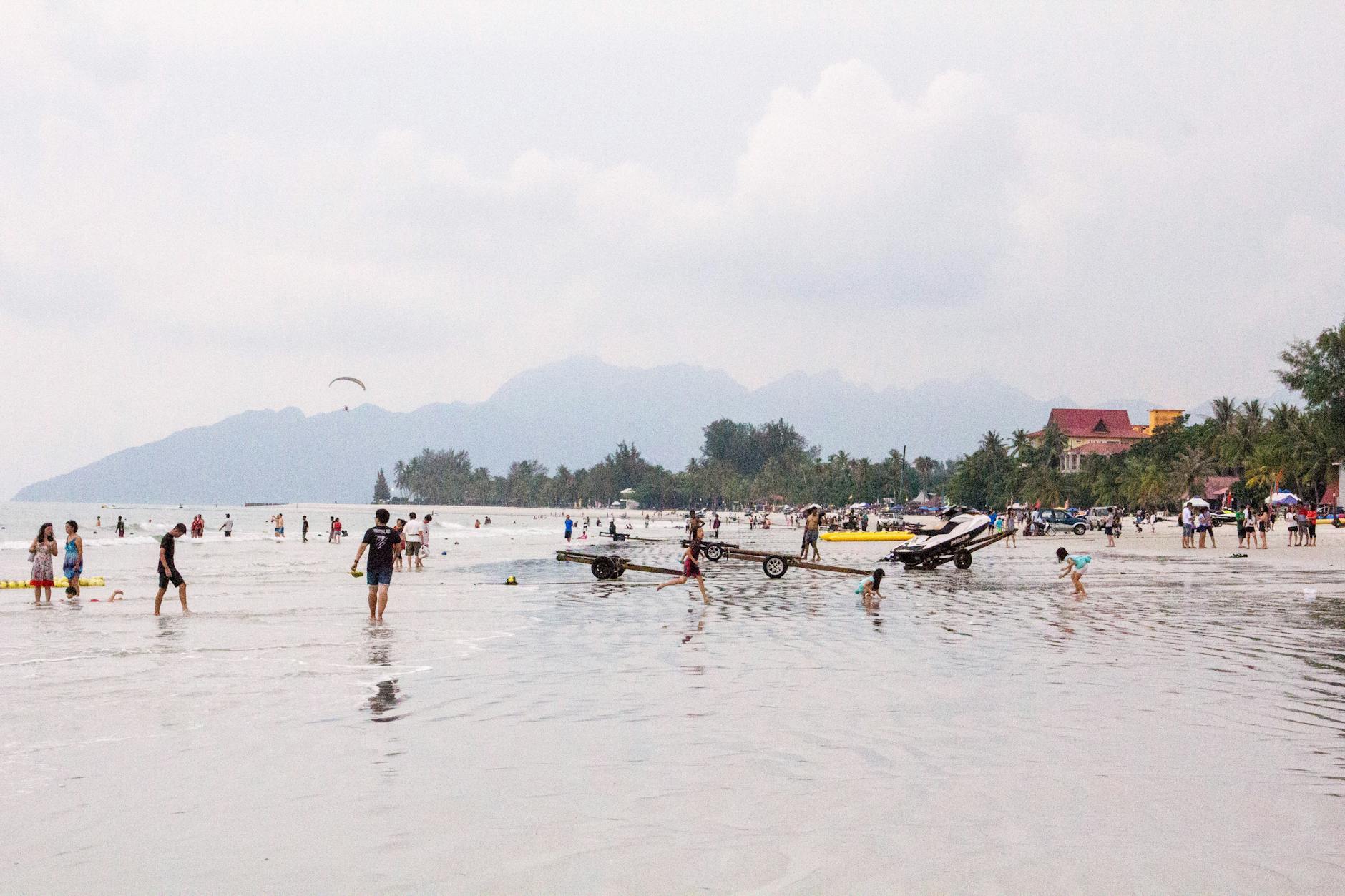 Vibrant beach day in Langkawi with people enjoying summer activities.