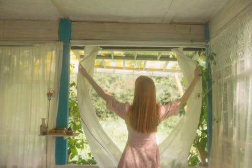 Jovem elegante abrindo cortinas em Coimbra