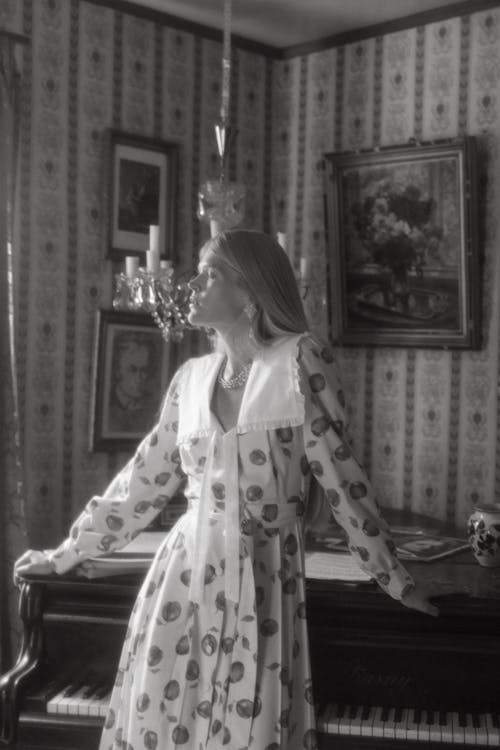 A Woman in Printed Dress Standing Near a Piano