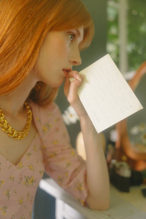 Woman Holding a Paper near her Mouth