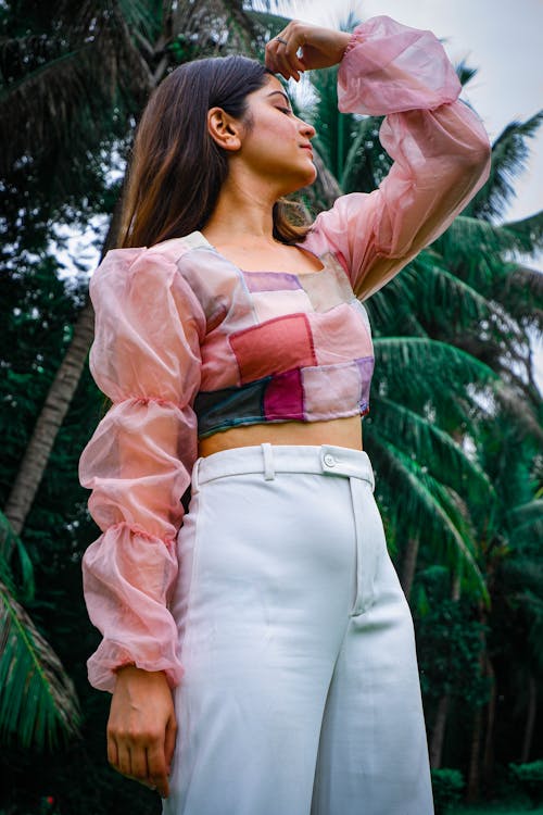 Woman in Pink Long Sleeve Blouse and White Pants Posing