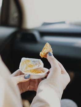 Close-up of hands holding a snack dip with manicured nails, indoors.