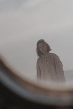 A young woman with a thoughtful expression looking through an airplane window in daylight.
