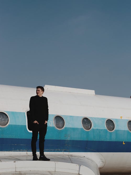 A Man Wearing black Clothes Standing on the Airplane Wing