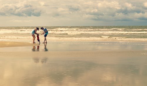 Free 2 Men and Woman Walking on Beach Stock Photo
