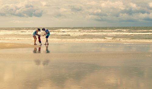 Free A family enjoying playtime by the shore at Sunset Beach, NC under a clear sky. Stock Photo