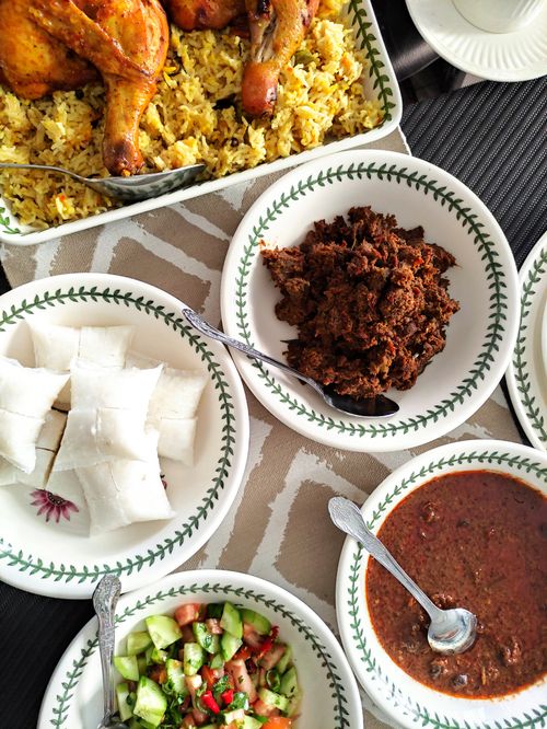 Free Top view of a vibrant African meal featuring chicken, rice, salad, and sauces in ceramic bowls. Stock Photo