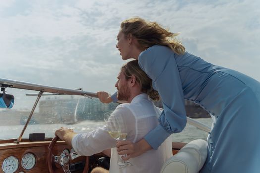 A couple on a boat, enjoying a champagne toast on a sunny day at sea.