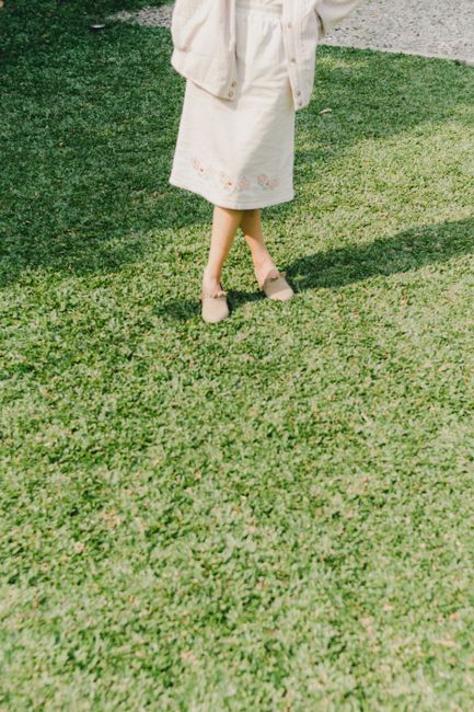A person stands on sunlit green grass, creating a clear shadow.