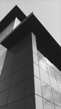 Striking low angle shot of modern glass building in monochrome, emphasizing architectural design.