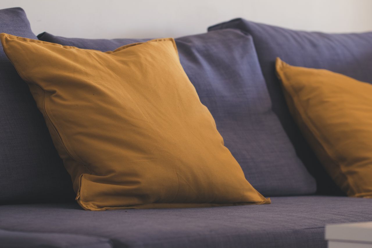 Close-up of mustard yellow cushions on a dark gray sofa showing pillow scale