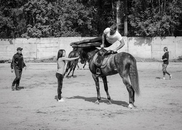 Grayscale Photo Of Man Jumping Off A Horse