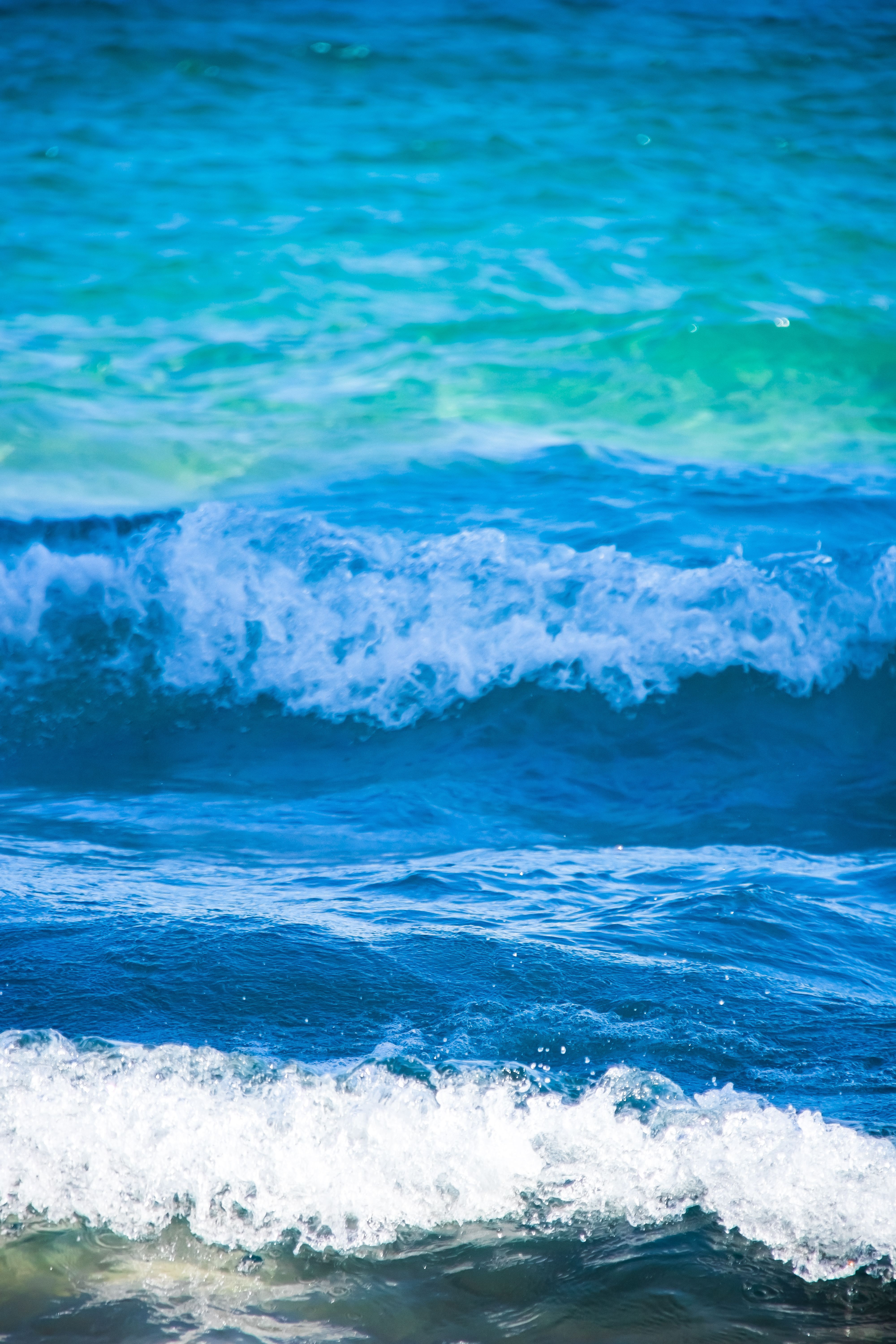 Fotomural Primer plano dinámico de olas turquesas rompiendo en la playa de Benidorm, mostrando el poder de la naturaleza.