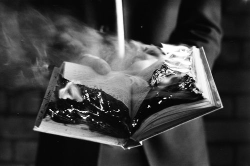Free A striking black and white photo of a book engulfed in flames, emitting smoke. Stock Photo