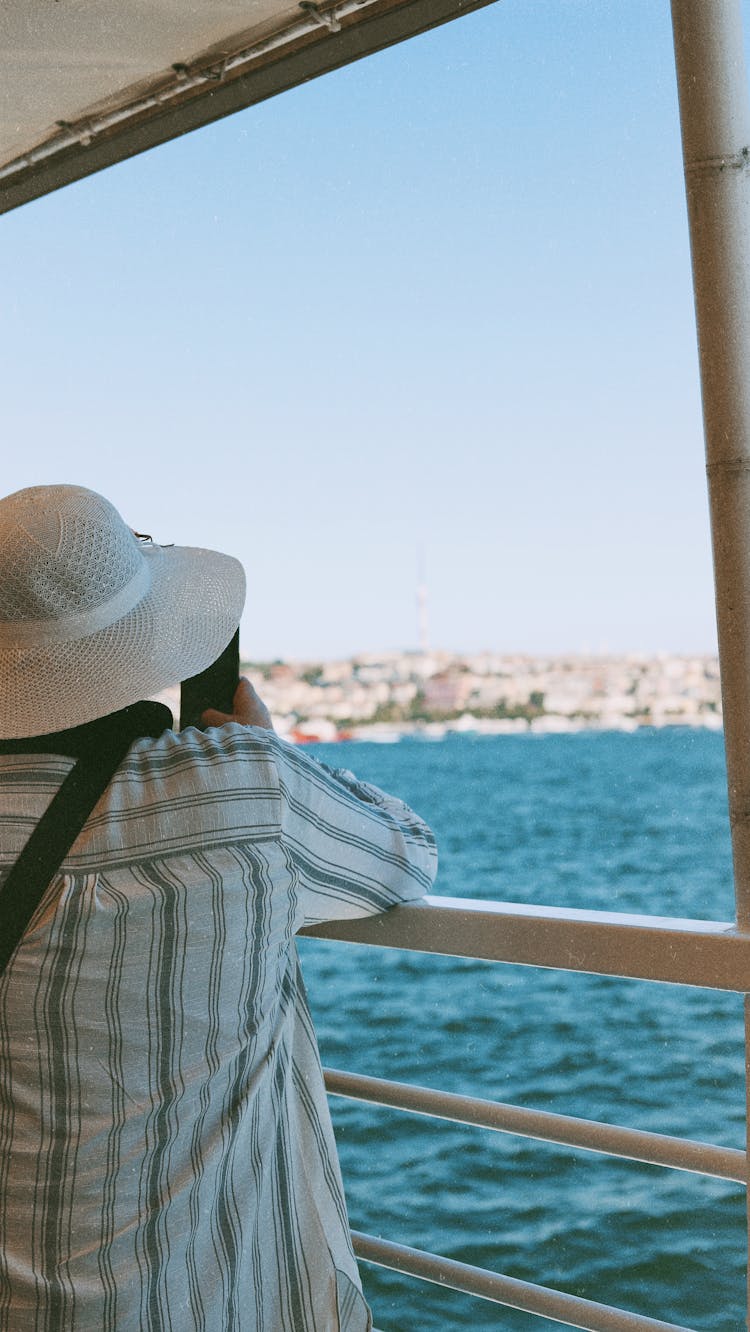 Person In Hat Taking Picture Of Sea From Boat