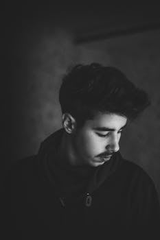 一位年轻人的黑白艺术肖像以侧面视角呈现，流露出喜怒无常又内省的氛围