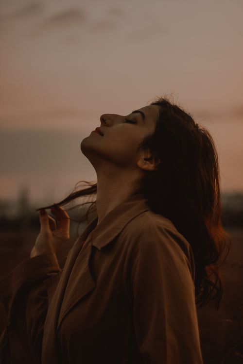 Free Profile of a woman in a brown coat, eyes closed, embracing the serene sunset outdoors. Stock Photo