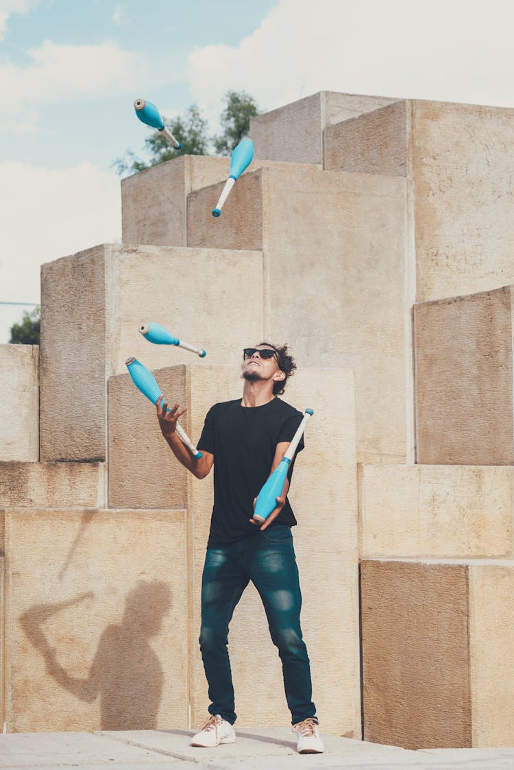 Man In Black Shirt Juggling Blue Pins